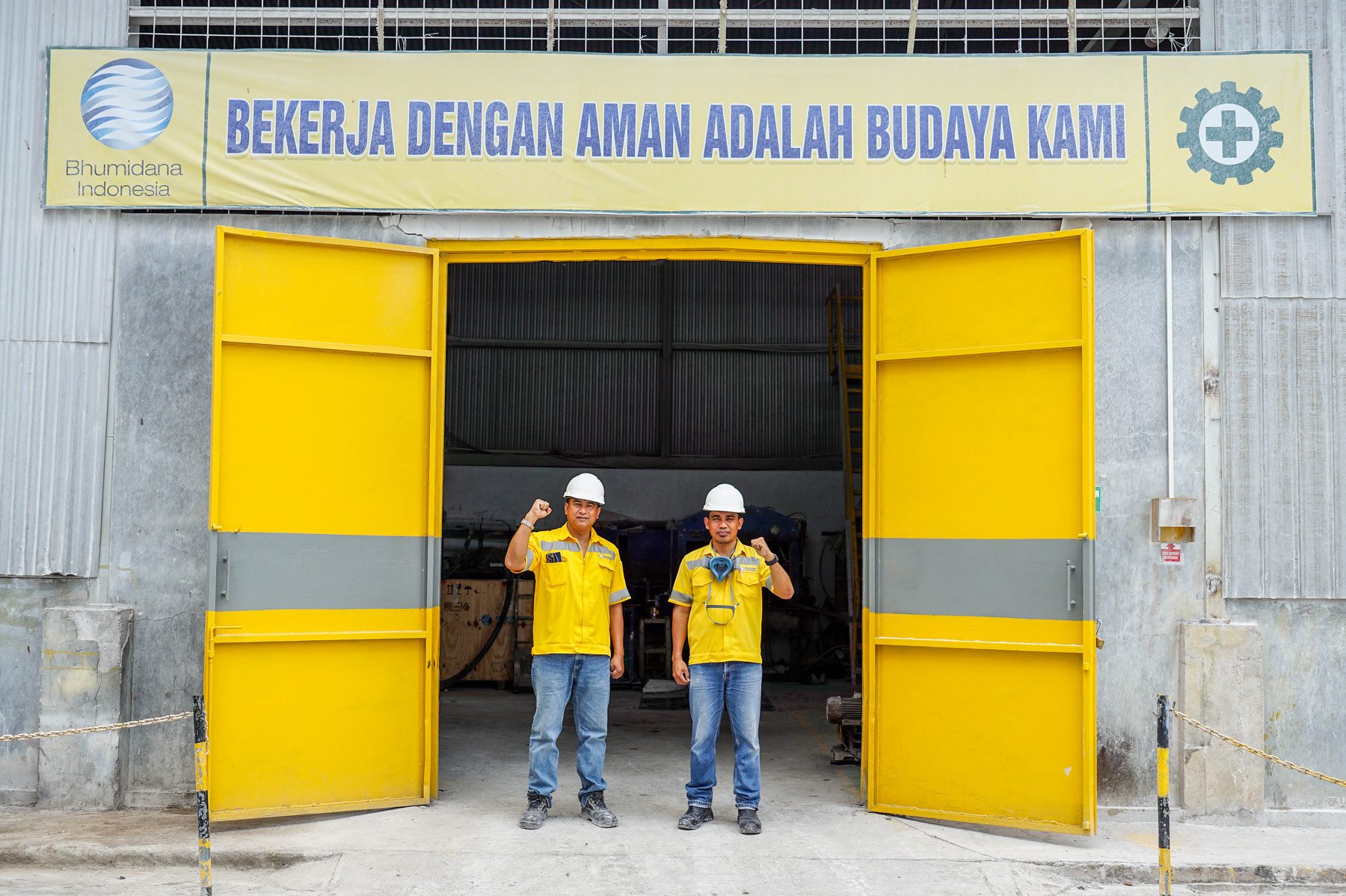 Two Bhumidana team members in safety gear at a plant entrance