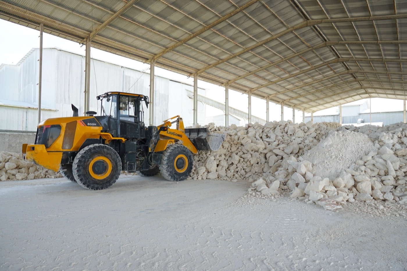 Wheel loader working a stockpile of white limestone